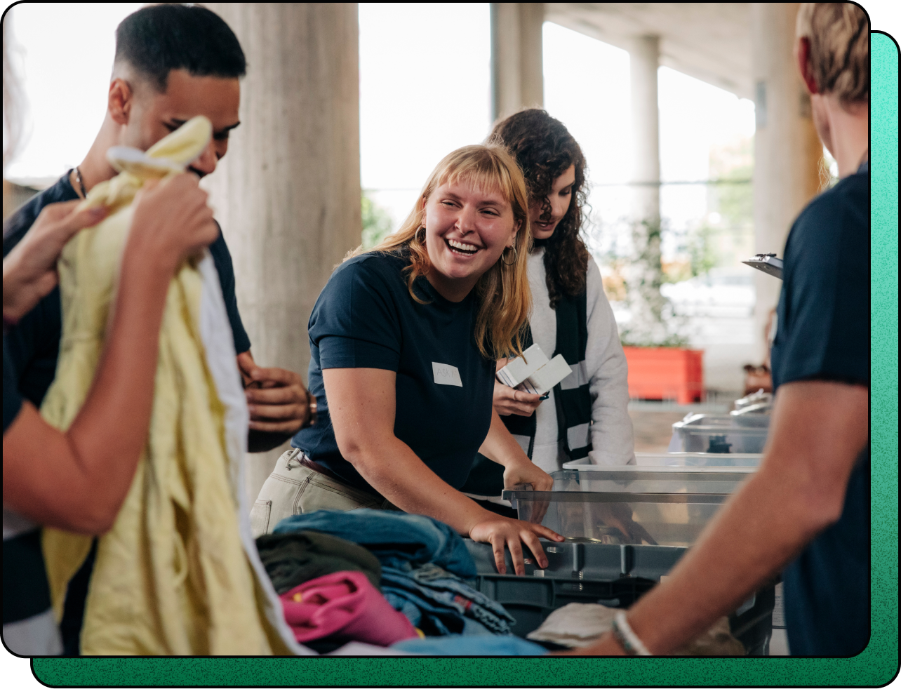 A group of smiling volunteers from a nonprofit organization happily folding clothing to support their community, highlighting their collaborative efforts supported by Sprout Social.