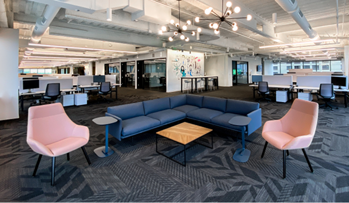 The Sprout Social office in Seattle, an open-plan space with a large L-shaped sofa, two armchairs and a wooden table.