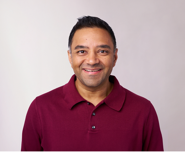 Headshot of Srinivas Somayajula, Chief Product Officer, wearing a red top.​​ 