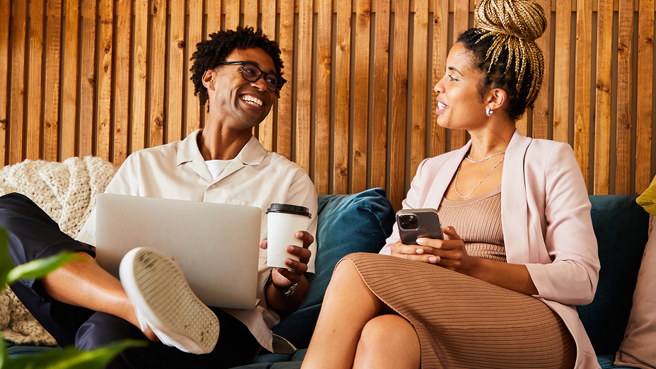 Dos personas en un sofá sonriendo y mirándose, que representa las conexiones humanas positivas que se fomentan a través de las redes sociales.